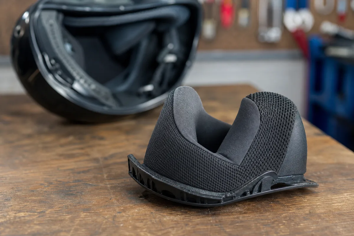 Gros plan sur une mousse de joue de casque moto retirée, posée sur un établi d&rsquo;atelier